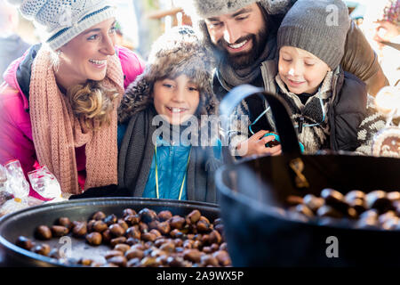 Familie auf den Weihnachtsmarkt Essen süße gebratene Kastanien Stockfoto