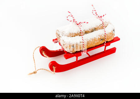 Nahaufnahme der Stollen, ein Deutscher Christstollen, Rot, Holz Schlitten isoliert auf Weiss. Hohe Blickwinkel betrachten. Stockfoto