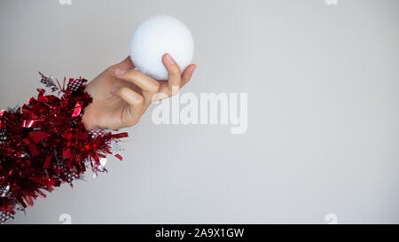 Woman's Hand gewickelt mit dekorativen Streamer auf das Neue Jahr mit einem Schneeball. Stockfoto