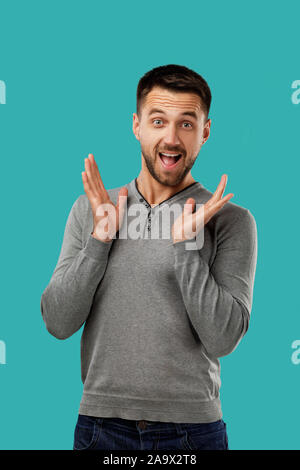 Porträt der jungen überrascht glücklich aussehenden bärtigen Mann auf blauem Hintergrund. Stockfoto
