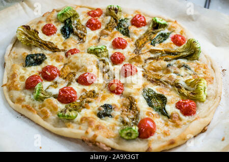 Echte italienische Pizza mit Zucchini Blumen, Gemüse und Tomaten. Traditionelle biologische Lebensmittel. Stockfoto