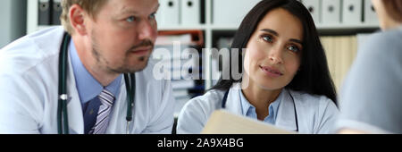 Junge Frau fragt Gruppe von GP für Heilung von Krankheit Stockfoto