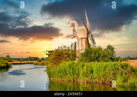 Mühle bei Sonnenuntergang auf dem Fluss Ant in der Nähe von Ludham Brücke, auf der Norfolk Broads in Norfolk, England. Stockfoto