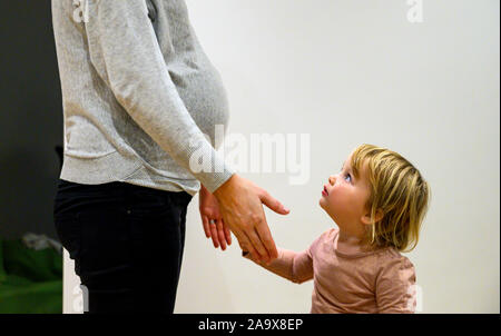 Schwangere Mutter mit zwei Jahre alten Tochter und Babybauch Fotografie von Simon Dack Stockfoto