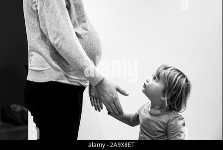 Schwangere Mutter mit zwei Jahre alten Tochter und Babybauch Fotografie von Simon Dack Stockfoto