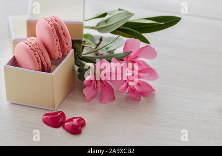 Rosa Makronen in Geschenkbox mit Blumenstrauß und zwei Herzen. Liebe und Romantische vorliegenden Konzept. Saint Valentine's Day Feier Karte. Platz kopieren Stockfoto