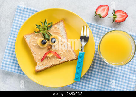 Peanut Butter Sandwich mit lustigen wütend das Gesicht und ein Glas Orangensaft für die Kinder. Tabelle Ansicht von Oben. Gesunde Ernährung Stockfoto