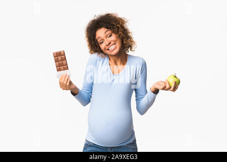 Schwangerschaft Ernährung. Schwangere Frau die Wahl zwischen Apple und Schokolade Stockfoto