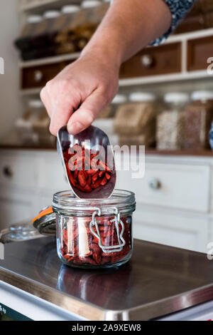 In der Nähe der Person wiegen Goji Beeren in Glas Glas auf Küchenwaagen. Stockfoto