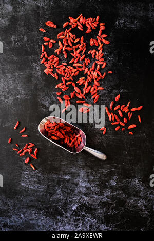 Hohen winkel Nahaufnahme von Goji Beeren und Metall Schaufel auf schwarzen Hintergrund. Stockfoto