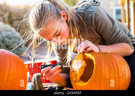 Ein junges Mädchen das Schnitzen eines großen Kürbis an Halloween. Stockfoto