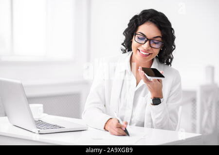 Happy Hispanic Frau mit Voice Assistant auf dem Smartphone Stockfoto