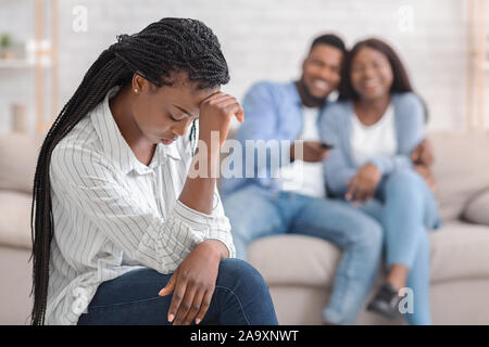 Eifersüchtig Mädchen sitzt allein, während Ihr dating Freunde Kuscheln auf dem Sofa Stockfoto