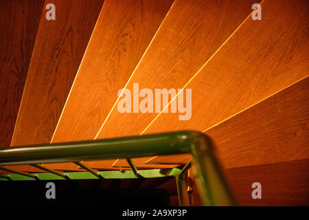 Abstrakte Shot mit einem Blick von oben auf das helle Holztreppe in der warmen Abendsonne in einem Haus und einem grünen Geländer aus Stahl Stockfoto