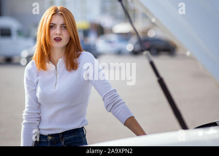 Jungen betonte Frau Fahrer in der Nähe von Broken Auto mit offener Haube. Stockfoto