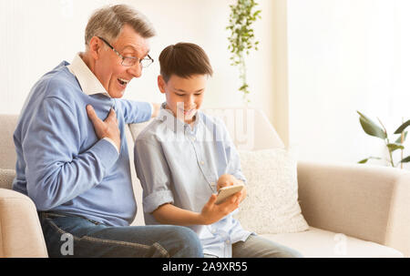 Junge Lehre Großvater zu Smartphone sitzen auf der Couch Indoor Stockfoto