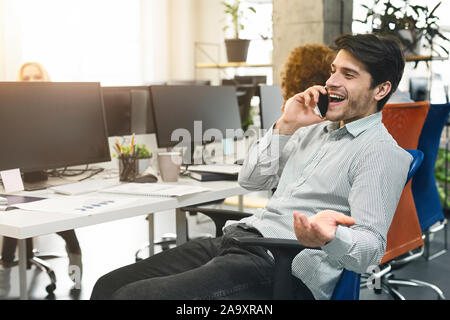 Freundliche Mann am Telefon sprechen am Arbeitsplatz Stockfoto