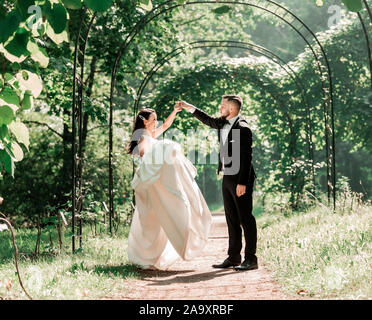 Glückliche Braut und Bräutigam Hochzeit tanzen unter dem Arch. Stockfoto