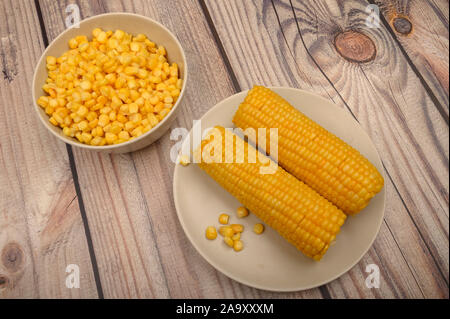 Zwei Ohren von gekochten Mais in eine Platte und ein Korn von Korn auf dem Tisch. Gesunde Ernährung. Fitness Ernährung. Für einen süßen Leckereien Stockfoto