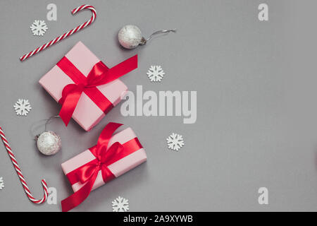 Winter Weihnachten Grenze Banner mit Papier rosa präsentiert, Zuckerstangen, Konfetti, silberne Kugeln auf grauem Hintergrund. Stockfoto