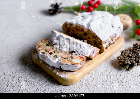 Christstollen auf Holz- fach an der konkreten Hintergrund. Traditionelle weihnachtliche Gebäck Dessert mit festliche Dekoration. Platz kopieren Stockfoto