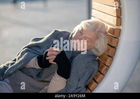 Frau trinkt Kaffee während die Ausgaben Tag draußen Stockfoto