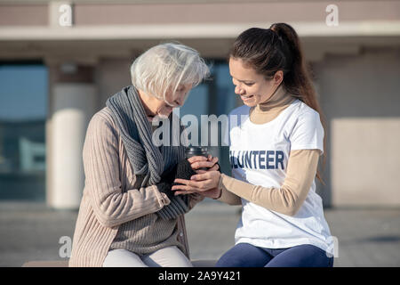 Lächelnd Freiwilligen einigen heißen Tee für arme Frau Frieren geben Stockfoto