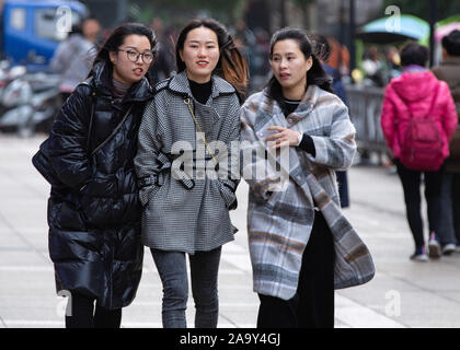 Trendige jungen chinesischen Frauen reagieren, als Sie zu Fuß auf der Straße in die Kaeltewelle in Nanjing, Provinz Jiangsu im Osten Chinas am 18. November, 2019. Stockfoto