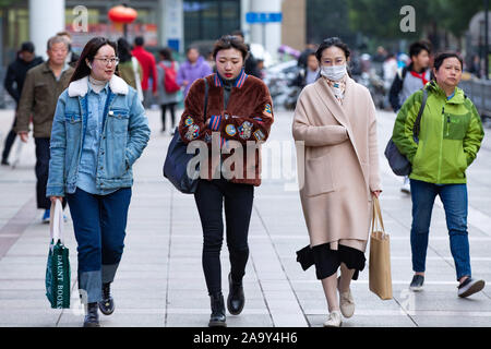 Trendige jungen chinesischen Frauen reagieren, als Sie zu Fuß auf der Straße in die Kaeltewelle in Nanjing, Provinz Jiangsu im Osten Chinas am 18. November, 2019. Stockfoto