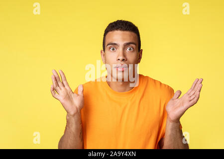 Schüttelte und clueless gutaussehenden jungen Mann, die Hände seitlich, zuckte unentschlossen, kann nicht sagen, weiß nicht, was sie spricht, verwundert, wie zu beantworten Stockfoto