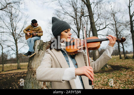 Duett von Geiger und Gitarristen spielen Musik in einem schönen Herbst Forrest Stockfoto