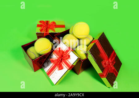 Tennis Bälle im Urlaub Geschenk Red Boxen als Geschenk für Weihnachten, Neujahr, Geburtstag am grünen Farbe Hintergrund. Kopieren Sie Platz. Winter Sport gesund Layout. Urlaub Konzeption. Stockfoto