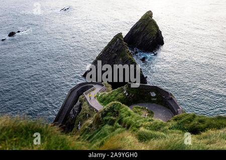 Mutter und Sohn gehen auf windige Straße nach Dunquin Hafen, in Dunquin, County Kerry, Republik von Irland Stockfoto