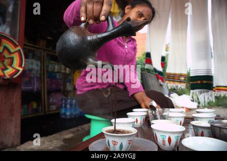 Lalibela/Äthiopien - 04/10/2019 :: Äthiopische Frau giesst äthiopischen Kaffee von traditionellen Kaffeekanne in kleinen Tassen Stockfoto