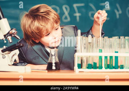 Schule Bildung. Biologische Moleküle erkunden. Kleinkind genius Baby. Junge in der Nähe von Mikroskop und Reagenzgläser in der Schule Klassenzimmer. Technik und Wissenschaft Konzept. Kid studiere Biologie und Chemie in der Schule. Stockfoto