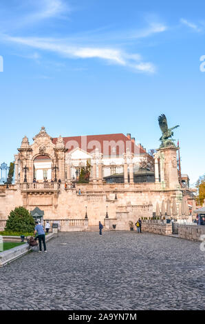 Budapest, Ungarn - Nov 6, 2019: historischen Innenhof der Burg von Buda. Statue des mythologischen Vogel Turul und historische Treppe im Hintergrund. Touristische Attraktion, Menschen auf dem Platz. Stockfoto