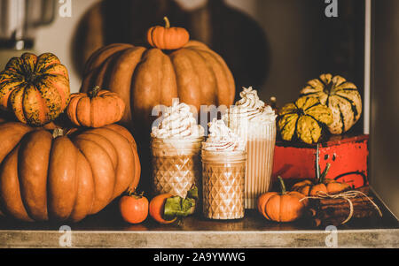 Kürbis latte Kaffee in Gläser unter Kürbisse und Zimtstangen Stockfoto