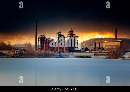 Alte metallurgischen Werk vor dem Hintergrund der dramatischen Sonnenuntergang im Winter. Stockfoto