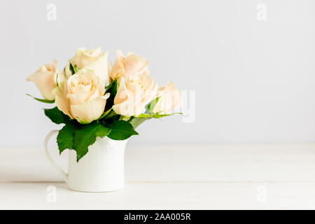 Romantisches Bouquet von pastellfarbenes Creme Rosen in einem Glas auf einem weißen Hintergrund. Für Text platzieren. Stockfoto