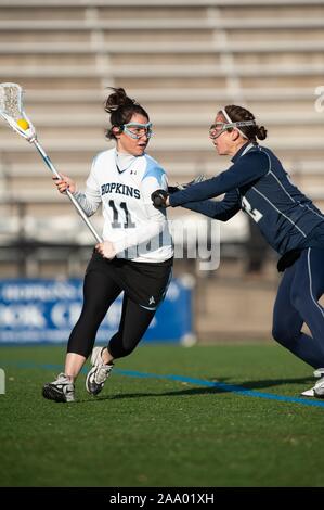 Ein Gegner versucht ein Johns Hopkins University Frauen Lacrosse Spieler, wiegt den Ball in ihr Netz während eines Spiels mit der Georgetown University, 25. Februar 2009 zu prüfen. Vom Homewood Sammlung Fotografie. () Stockfoto