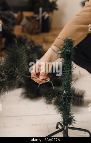 Man sammelt künstlicher Weihnachtsbaum zu Hause. Die Phase der Montage des Framing Baum. Anleitung und Hilfe. Stockfoto