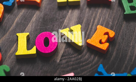 Holzbuchstaben bilden Wort Liebe geschrieben am hölzernen Hintergrund Stockfoto