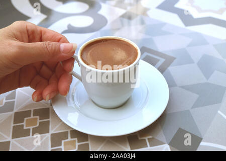Woman's Hand eine Tasse türkischen Kaffee serviert auf einem maurischen Muster Tabelle Stockfoto