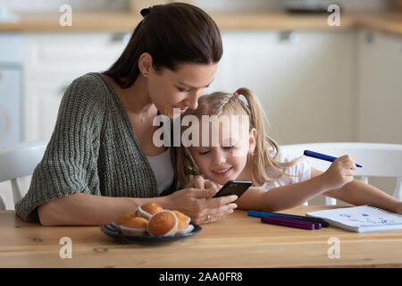 Von der Zeichnung wenig Vorschule Mädchen Spähen in Mutter s Smartphone abgelenkt. Stockfoto