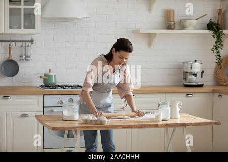 30 s Frau beugte sich über Tisch, Rollout von Teig. Stockfoto