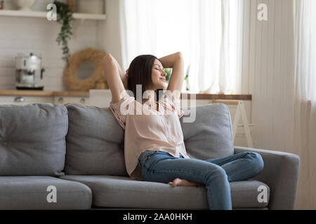 Glückliche junge Frau lag auf der Couch im Wohnzimmer. Stockfoto