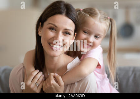 Lächelnd Vorschule Mädchen kuscheln zurück glückliche junge Mutter. Stockfoto