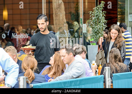 Ein Kellner liefert Speisen auf der Restaurantterrasse von Nando in der City of Westminster, London Stockfoto