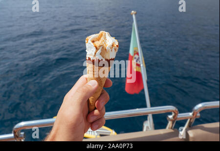 Eis in der Waffel Becher in der Hand des Mannes auf der Yacht Stockfoto