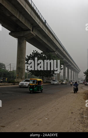 Das Verkehrsaufkommen durch und unten die schnelle U-Bahn Anschluss in Sektor 55 Gurgaon, die ungesunde Smog, die Auswirkungen auf die Gesundheit. Delhi Stockfoto